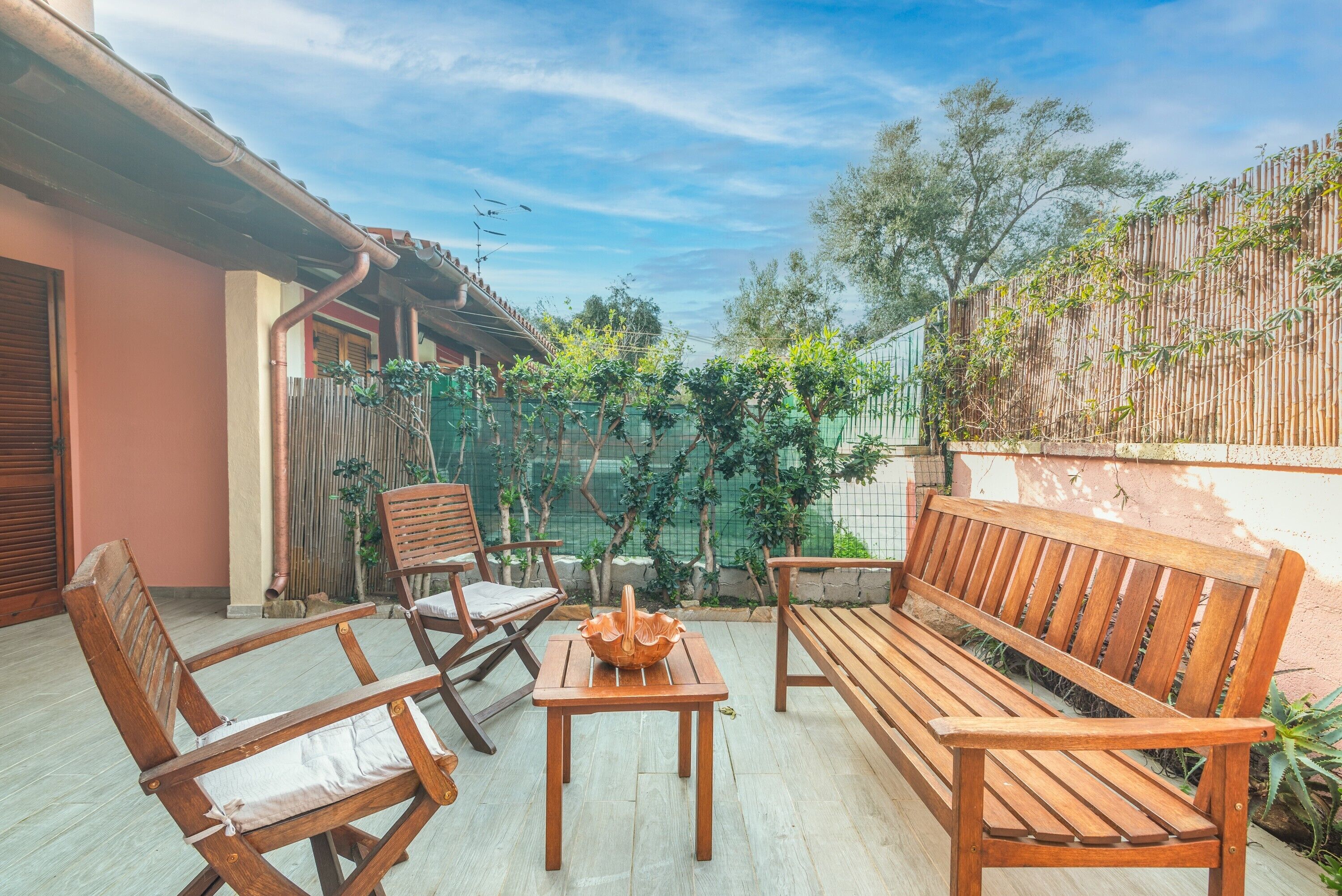 A patio with wooden furniture, a table, and a bench.