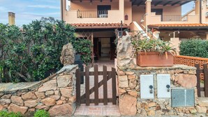 A two-story building with a stone entrance gate, a balcony, and a tiled roof.