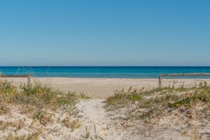 A beach with a sandy shore and a wooden fence in the foreground.