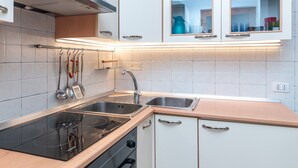 A modern kitchen with a stove, oven, two sinks, and white cabinetry.