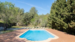 A rectangular swimming pool with a tiled deck, surrounded by trees and white lounge chairs. - Holiday Home 'La Xaconera' with Private Pool, Wi-Fi and Air Conditioning (Riera de Gaia)