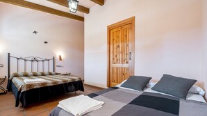 A bedroom with a bed, a wooden door, and a nightstand with a lamp. - Holiday Home 'La Xaconera' with Private Pool, Wi-Fi and Air Conditioning (Riera de Gaia)