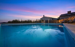 Relax by the serene pool, surrounded by a tiled edge and adjacent to a stone wall.