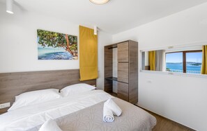 Relax in a stylish room with a comfortable bed, a large painting of a tropical beach scene, and a wardrobe with a mirror.
