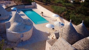 Une piscine dotée d’une architecture en pierre et agrémentée de parasols.
