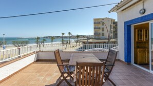 A balcony with a table and chairs, overlooking a beach and ocean. - Apartment 'Mimosa' with Sea View, Wi-Fi and Air Conditioning (L'Escala)