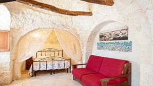 Una habitación con una cama, un sofá rojo, una pared de piedra y un cuadro en la pared.