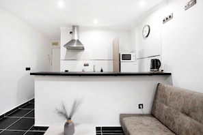 A modern kitchen with a microwave, stove, and ventilation hood. - Studio Apartment 'Estudio Centro De Torremolinos' with Wi-Fi and Air Conditioning (Torremolinos)