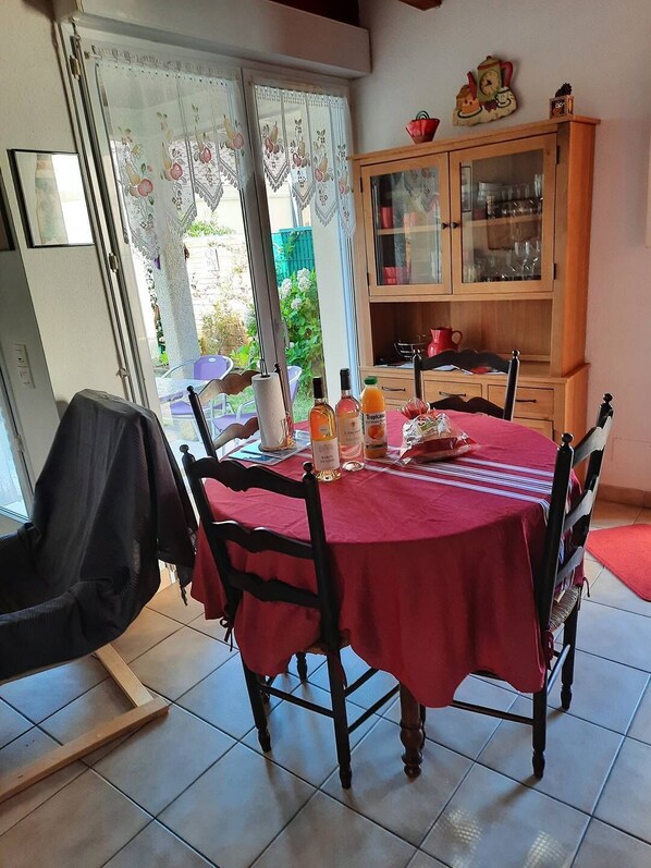 Un comedor con mantel rojo, sillas de madera y un aparador con puertas de vidrio.