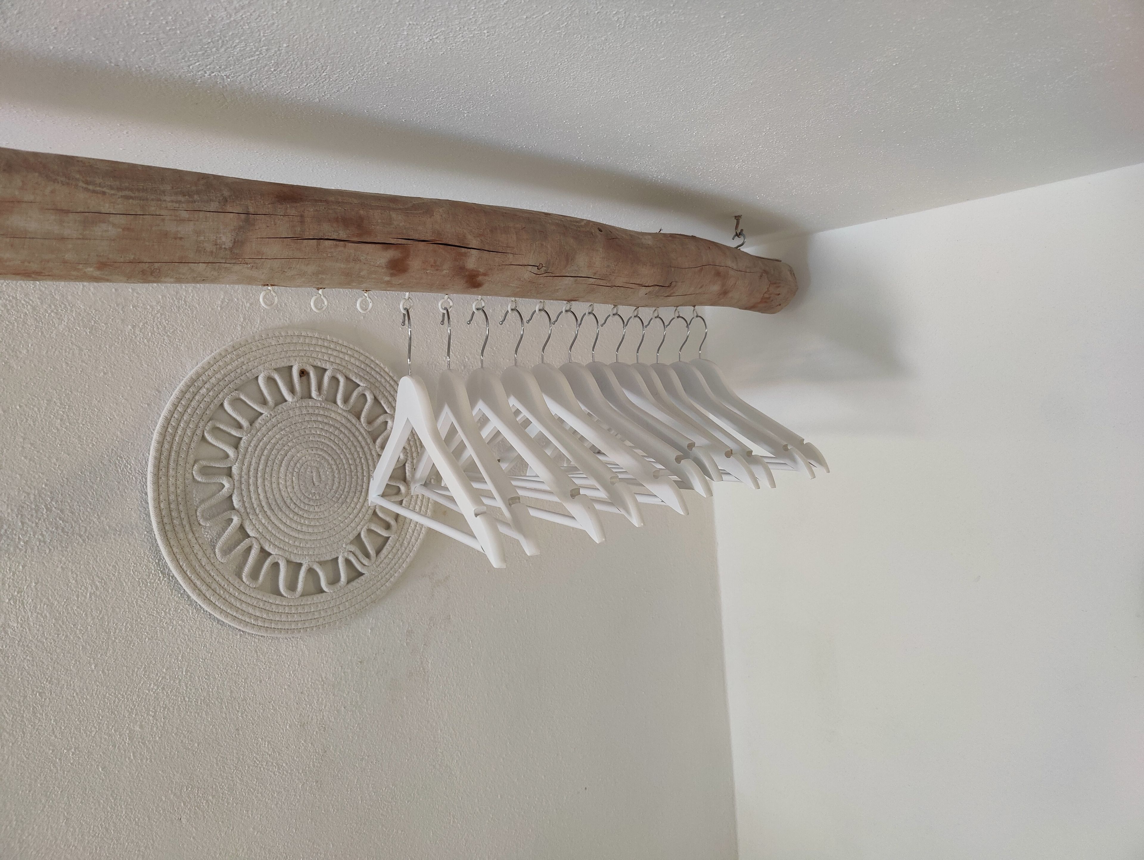 Un mur avec une poutre en bois et une décoration murale blanche, ornée de cintres blancs.