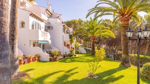 A courtyard with a white building, palm trees, and a lamp post. - Studio Apartment 'Sillero Dos' with Shared Pool, Wi-Fi and Air Conditioning (Moraira)