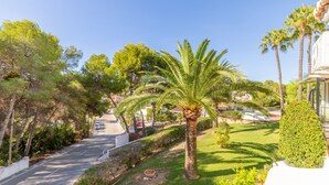 A residential street with palm trees, a grassy area, and a white building with a balcony. - Studio Apartment 'Sillero Dos' with Shared Pool, Wi-Fi and Air Conditioning (Moraira)