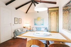 Un comedor con una mesa de madera, sillas, un ventilador de techo, un reloj en la pared y una puerta.