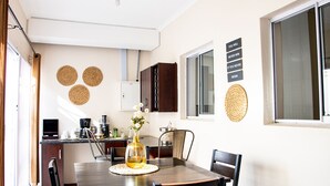 A compact kitchen with a dining area, including a table with chairs, a coffee machine, and a vase with flowers. - Mmaset Houses 3-bedrooms (Gaborone)