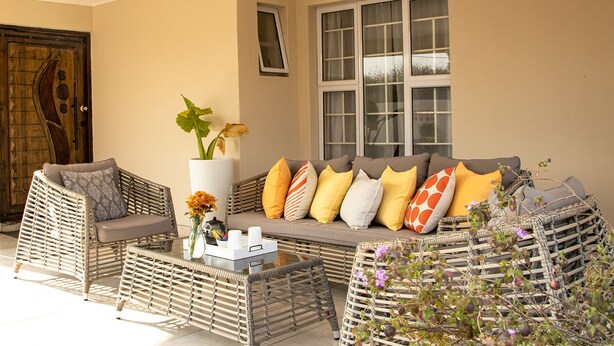 A cozy seating area with wicker furniture, a vase with flowers, and a window with curtains. - Mmaset Houses 3-bedrooms (Gaborone)