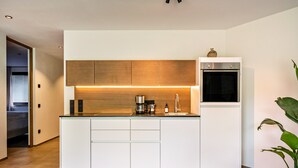 Een moderne keuken met een centraal eiland, een inbouwoven en houten keukenkastjes.