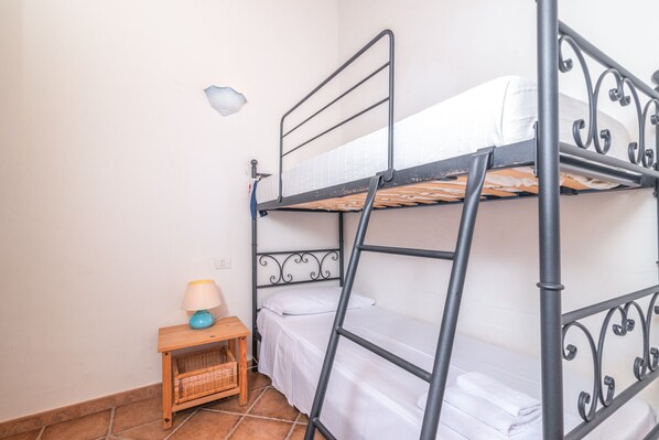 A bunk bed room with a small wooden nightstand and a lamp.