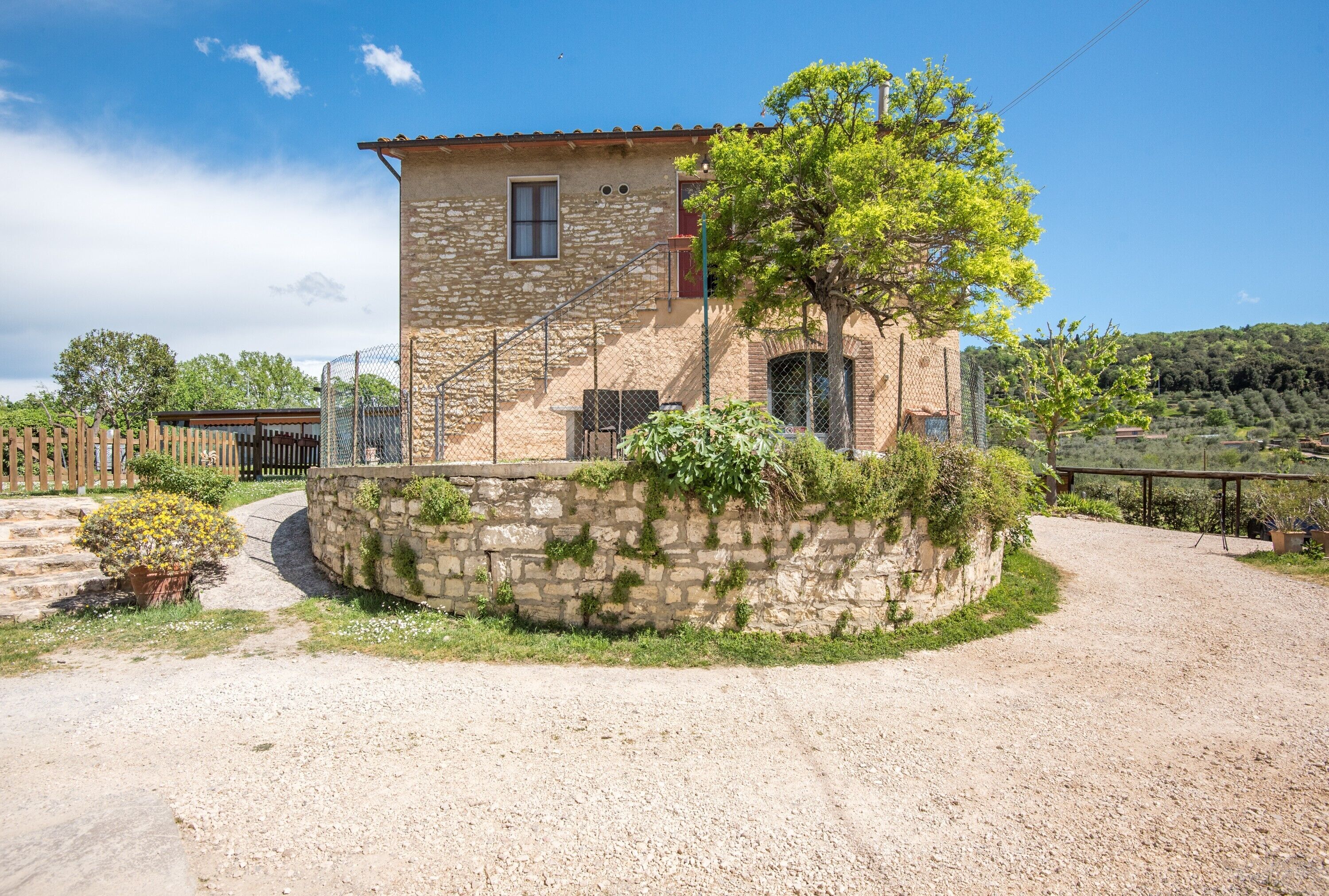 Un bâtiment en pierre avec un toit rouge, une petite fenêtre et un arbre devant.