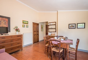 A dining area with a table set for four, wooden chairs, a red and white checkered tablecloth, and a cabinet with shelves. - Farmhouse 'Podere Del Pereto Bio- 202' with Shared Pool, Private Garden and Wi-Fi (Rapolano Terme)