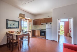Una cucina con mobili in legno, un tavolo da pranzo con sedie, un lampadario e un quadro appeso al muro.