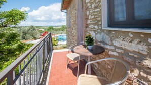 Un balcon avec une table et des chaises, un pot de fleurs et une vue sur la campagne.