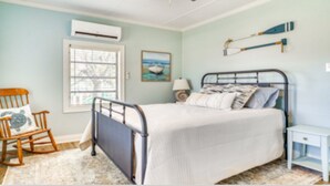 A bedroom with a bed, a rocking chair, a bedside table, a lamp, and a wall-mounted shelf. - The Salty Point....a waterfront fishing cottage with kayaks, ping pong and more! (Franklin)