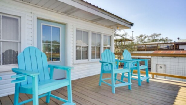 A wooden deck with two turquoise Adirondack chairs and a white building with large windows. - The Salty Point....a waterfront fishing cottage with kayaks, ping pong and more! (Franklin)