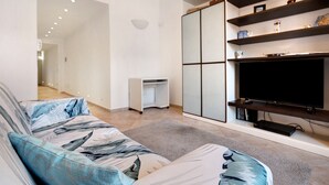 Un salon moderne avec un canapé, un téléviseur et des étagères.