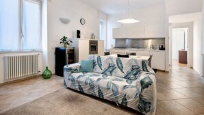 Un salon moderne avec un canapé, une table basse et une cuisine en arrière-plan.