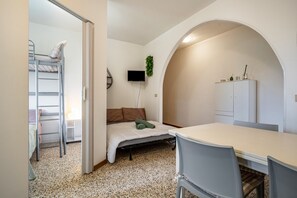 A bedroom with a bunk bed, a desk, and a television.
