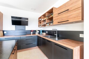 Una cocina moderna con armarios negros, encimeras de madera y horno empotrado.