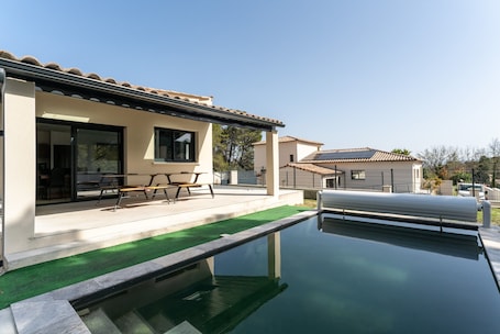 A modern house with a swimming pool, patio, and a covered outdoor seating area.
