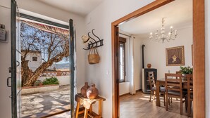 Una stanza con pavimento in legno, un tavolo da pranzo con sedie, un lampadario e vista su un albero all'esterno.