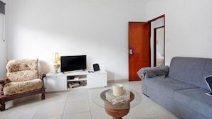 Ein Wohnzimmer mit Sofa, Sessel, Fernseher und Couchtisch.