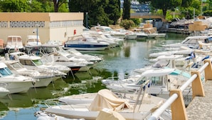 A marina with numerous boats docked in calm waters, surrounded by trees and a building with a beige facade. - Apartment 'Des Vacances De Rêve À Mandelieu' with Shared Pool and Air Conditioning (Mandelieu-la-Napoule)