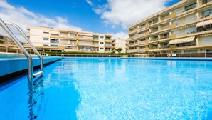 A swimming pool with a metal ladder, surrounded by multi-story buildings with balconies and awnings. - Apartment 'Des Vacances De Rêve À Mandelieu' with Shared Pool and Air Conditioning (Mandelieu-la-Napoule)