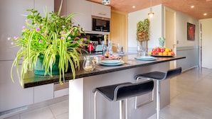 A modern kitchen with a central island, bar stools, and a potted plant. - Apartment 'Des Vacances De Rêve À Mandelieu' with Shared Pool and Air Conditioning (Mandelieu-la-Napoule)