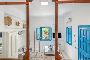 Una habitación con un armario blanco, una mesa de comedor con sillas, un ventanal azul y un techo blanco.