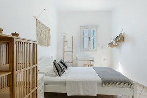 Une chambre à coucher comprenant un lit, un bureau, une armoire et une décoration murale en macramé.