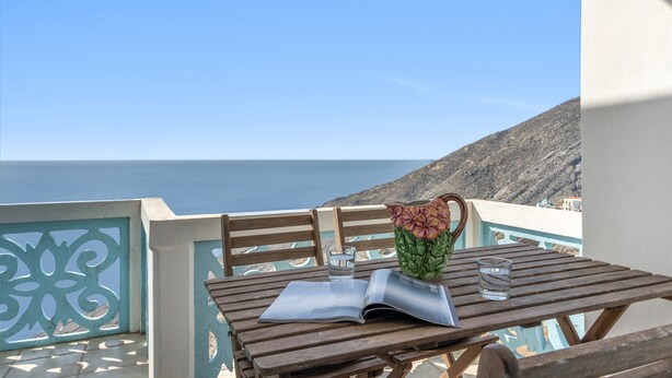 A wooden table with a book and a vase, overlooking a coastal view.