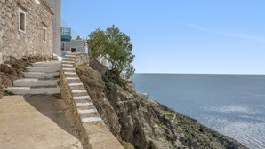 A coastal building with stone steps leading to a terrace overlooking the sea.