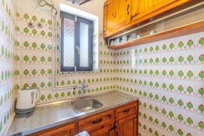 A kitchen with a sink, wooden cabinets, and patterned tiles. - Apartment 'Mires House  11' with Sea View, Wi-Fi and Air Conditioning (Corfu)