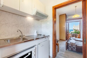 A compact kitchen with a sink, stove, and a view to a balcony with outdoor seating.