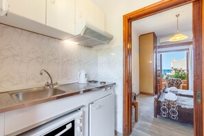 A modern kitchen with a sink, stove, and a view of a balcony with a table and chairs.