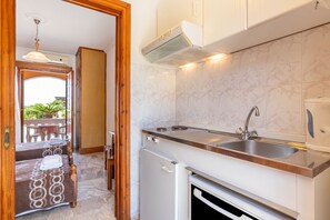 Una cocina compacta con horno integrado, un lavamanos y una campana extractora.