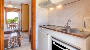 A compact kitchen with a built-in oven, a sink, and a ventilation hood.
