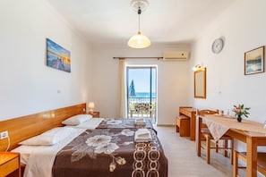 Quarto de hotel com duas camas, uma escrivaninha, uma cadeira, uma mesa com um vaso, um relógio e uma janela com vista.