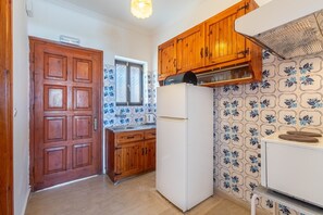 Eine Küche mit Holzschränken, einem weißen Kühlschrank und blauen Fliesen mit Blumenmuster.