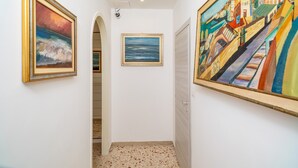 Un pasillo con dos cuadros enmarcados en las paredes, una puerta y un suelo con diseño.