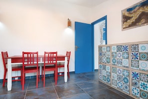 Un comedor con una mesa y sillas rojas, una puerta azul y un muro de azulejos con un diseño decorativo.